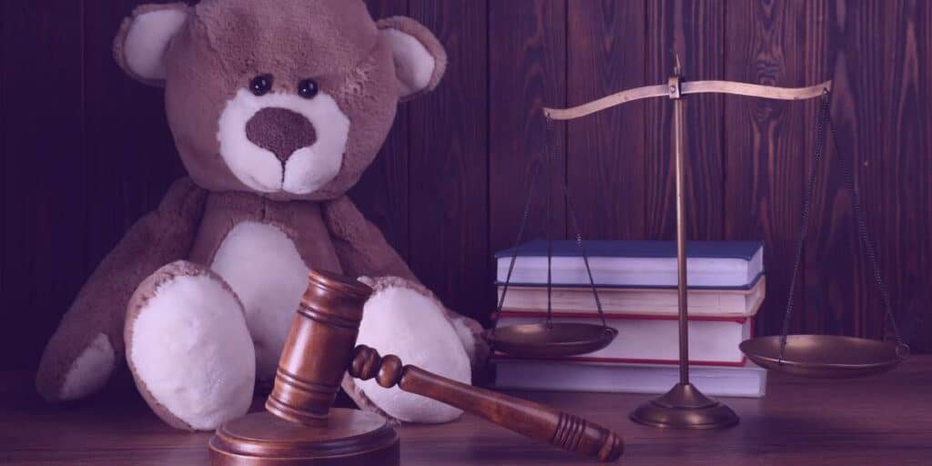 Um ursinho, um martelo, uma balança da justiça e a estátua da justiça representando a guarda unilateral.
